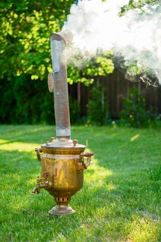 Traditional russian Samovar heating and boiling water in a summer garden