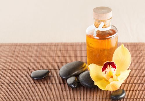 spa, health and beauty concept - closeup of essential oil, massage stones and orchid flower