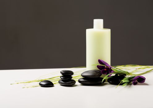 spa, health and beauty concept - closeup of shampoo bottle, massage stones and iris flower