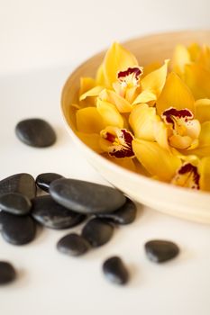 spa, heath and beauty concept - massage stones with orchid flowers on table