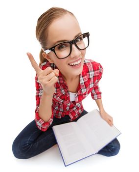 education and leisure concept - smiling teenage girl in black eyeglasses reading book