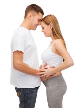 pregnancy, parenthood and happiness concept - happy young family expecting child looking at each other