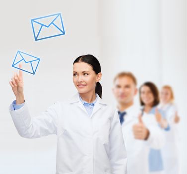 healthcare, medicine and technology concept - smiling female doctor pointing to envelope
