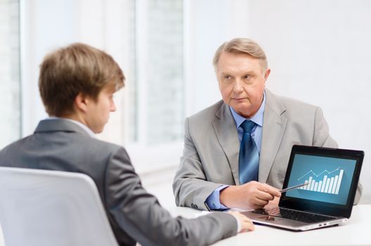 business, advertisement, technology and office concept - older man and young man with laptop computer in office