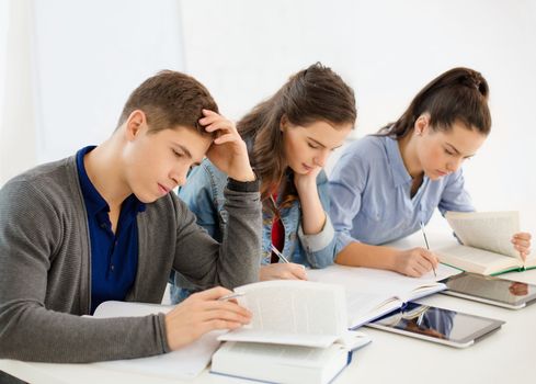 school and education concept - group of tired students with notebooks at school