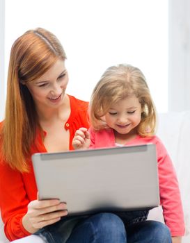 family, children, parenthood, technology and internet concept - happy mother and daughter with laptop computer at home