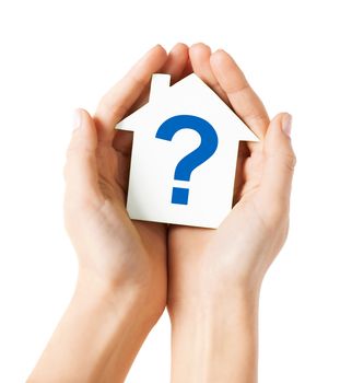 real estate and family home concept - hands holding paper house with question mark