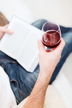 leisure, drinks, education and lifestyle concept - close up of male hand holdind book and glass of red wine