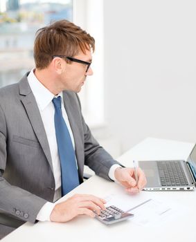 business, office, school and education concept - businessman with laptop computer, papers and calculator