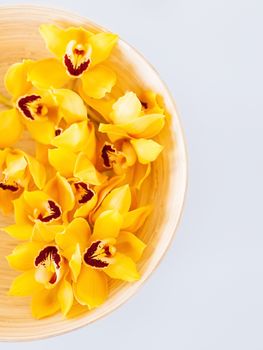 spa, health and beauty concept - closeup of wooden bowl with orchid flowers