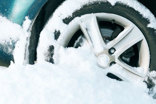 transportation, winter and vehicle concept - closeup of car wheel stuck in snow