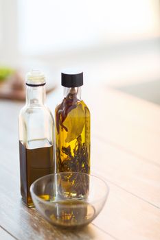 cooking and food concept - close up of two olive oil bottles and bowl of oil