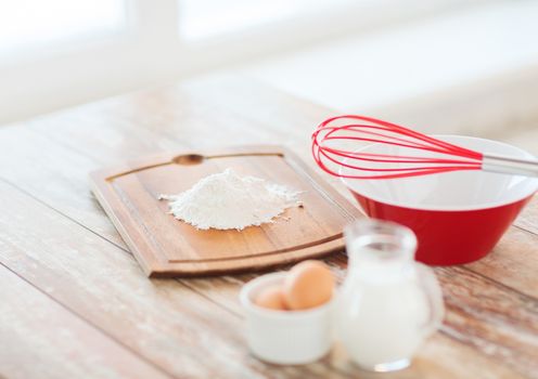 cooking and food concept - close up of jugful of milk, eggs in a bowl and flour