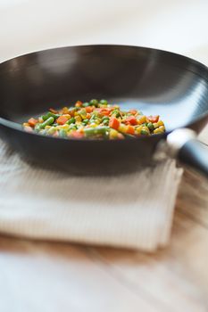 cooking, food and home concept - close up of wok pan with vegetables