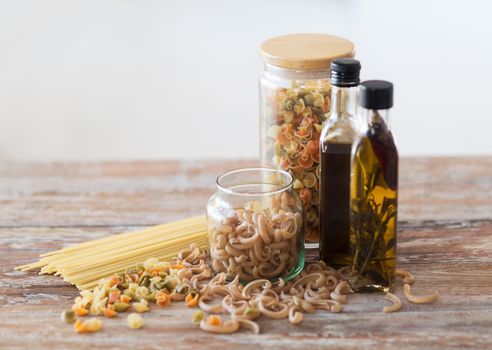 cooking and food concept - close up of two olive oil bottles and pasta in jars