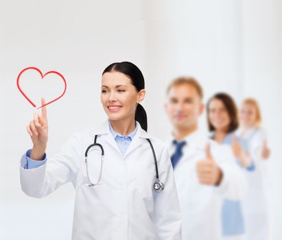 healthcare, medicine and technology concept - smiling female doctor pointing to heart