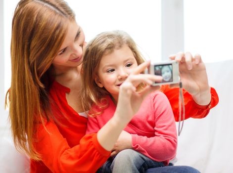 family, children, technology and happy people concept - smiling mother and daughter with digital camera