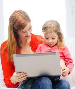 family, children, parenthood, technology and internet concept - happy mother and daughter with laptop computer at home