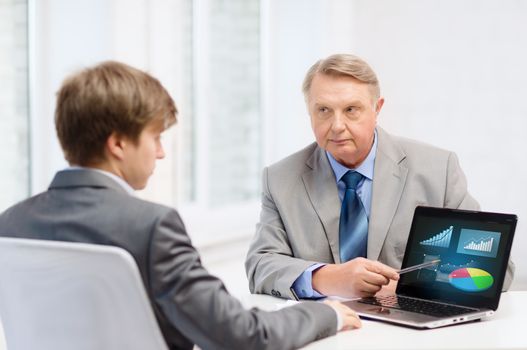 business, advertisement, technology and office concept - older man and young man with laptop computer in office