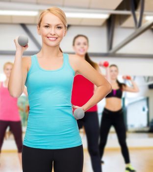 sport, excercising and healthcare concept - young sporty woman with light dumbbells