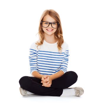 happiness and people concept - smiling girl in eyeglasses sitting on floor