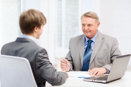 business, technology and office concept - older man and young man having meeting in office