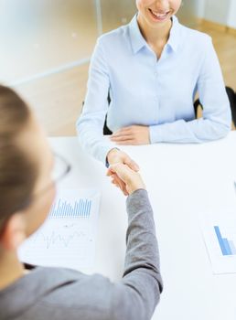 business and office concept - two smiling businesswoman shaking hands in office