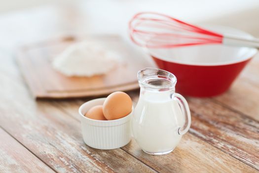 cooking and food concept - close up of jugful of milk, eggs in a bowl and flour