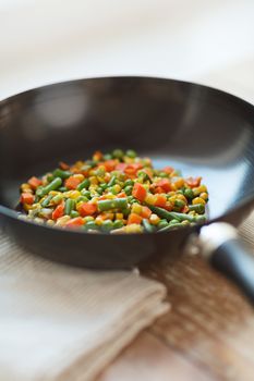 cooking, food and home concept - close up of wok pan with vegetables