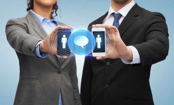 business, technology and internetconcept - businessman and businesswoman with social or business network on smartphone screens