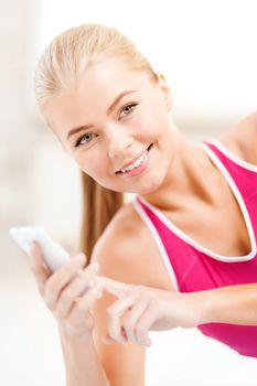 fitness, technology and exercise concept - smiling woman with smartphone