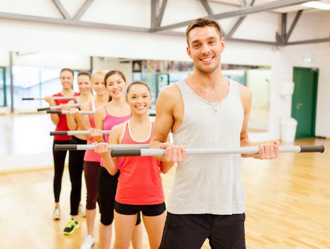 fitness, sport, training, gym and lifestyle concept - group of smiling people working out with barbells in the gym