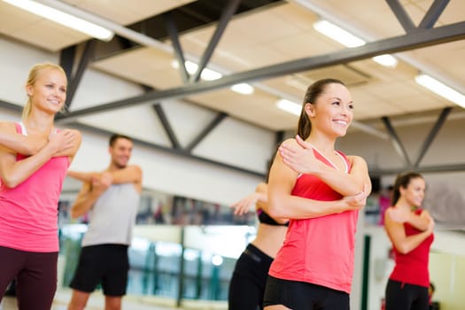 fitness, sport, training, gym and lifestyle concept - group of smiling people stretching in the gym