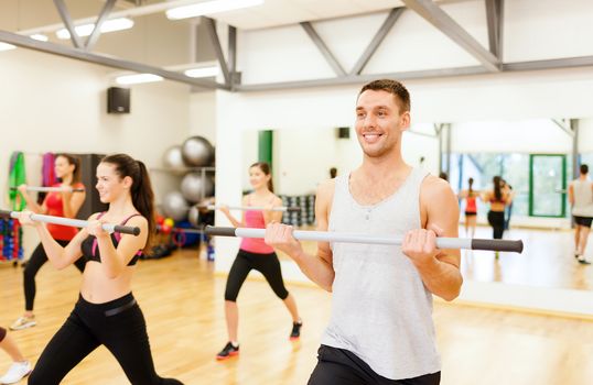 fitness, sport, training, gym and lifestyle concept - group of smiling people working out with barbells in the gym