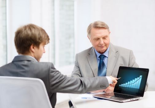 business, advertisement, technology and office concept - older man and young man with laptop computer in office