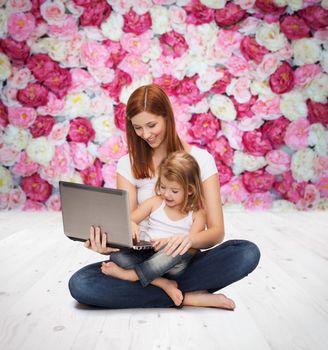 childhood, parenting and technology concept - happy mother with adorable little girl with laptop