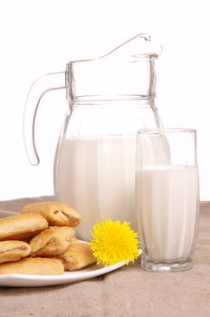 Milk jug and pastry on white background