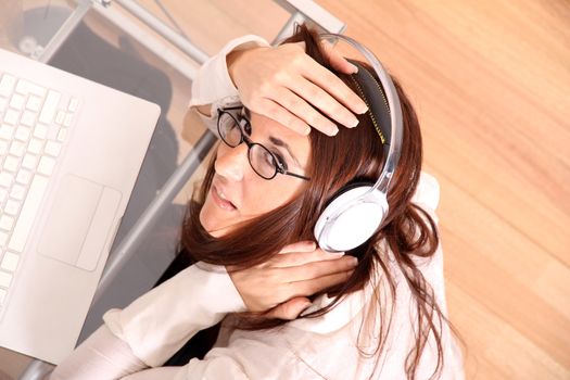 Business woman working on a Laptop while listening music with Headphones.