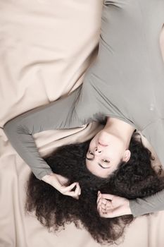 A young brazilian woman resting on a bed.