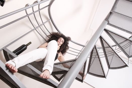 A young brazilian woman sitting on the stairs with a glass of red wine.