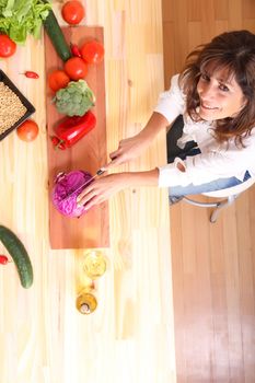 A beautiful mature woman cutting vegetables in the kitchen.