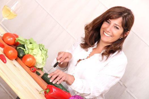 A beautiful mature woman cutting vegetables in the kitchen.