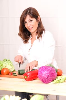 A beautiful mature woman cutting vegetables in the kitchen.