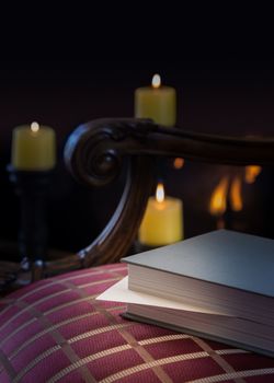 Envelope inserted into a book as a marker and left abandoned on a carved chair with firelight and candles in background to give a warm cozy winter feeling