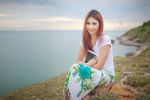 Young asian woman use tablet pc on mountain and sea