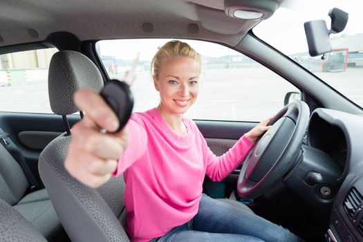 Woman driver showing car keys. Young female driving happy about her new car or drivers license. Caucasian model.