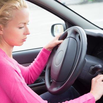 Beautiful casually dressed female car driver starting the engine.