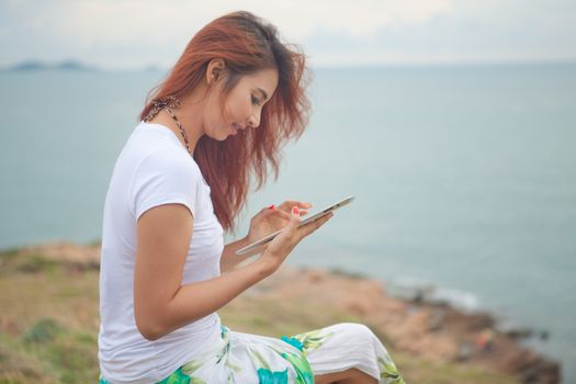 Young asian woman use tablet pc on mountain and sea