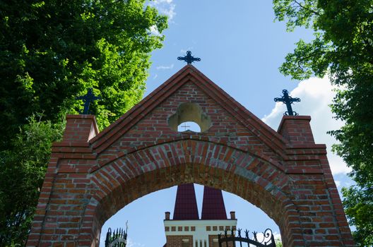 gothic church brick gate with small metallic crosses on blue sky background