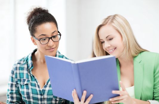 education concept - picture of smiling student girls reading book at school